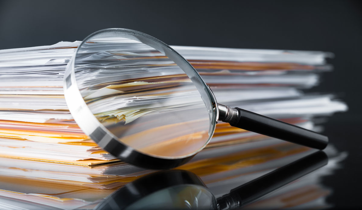 magnifying glass over stack of papers