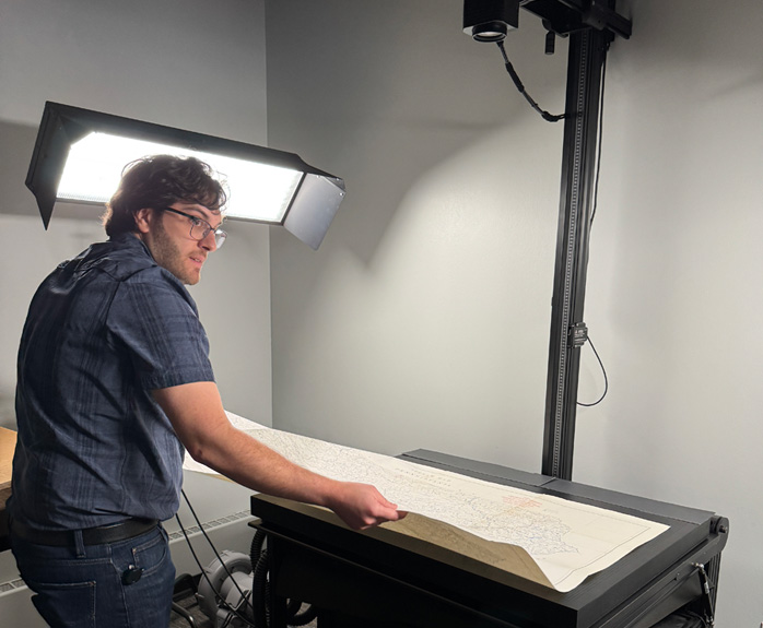 Archival technician digitizing a large historical map using a high-resolution, instant-capture camera